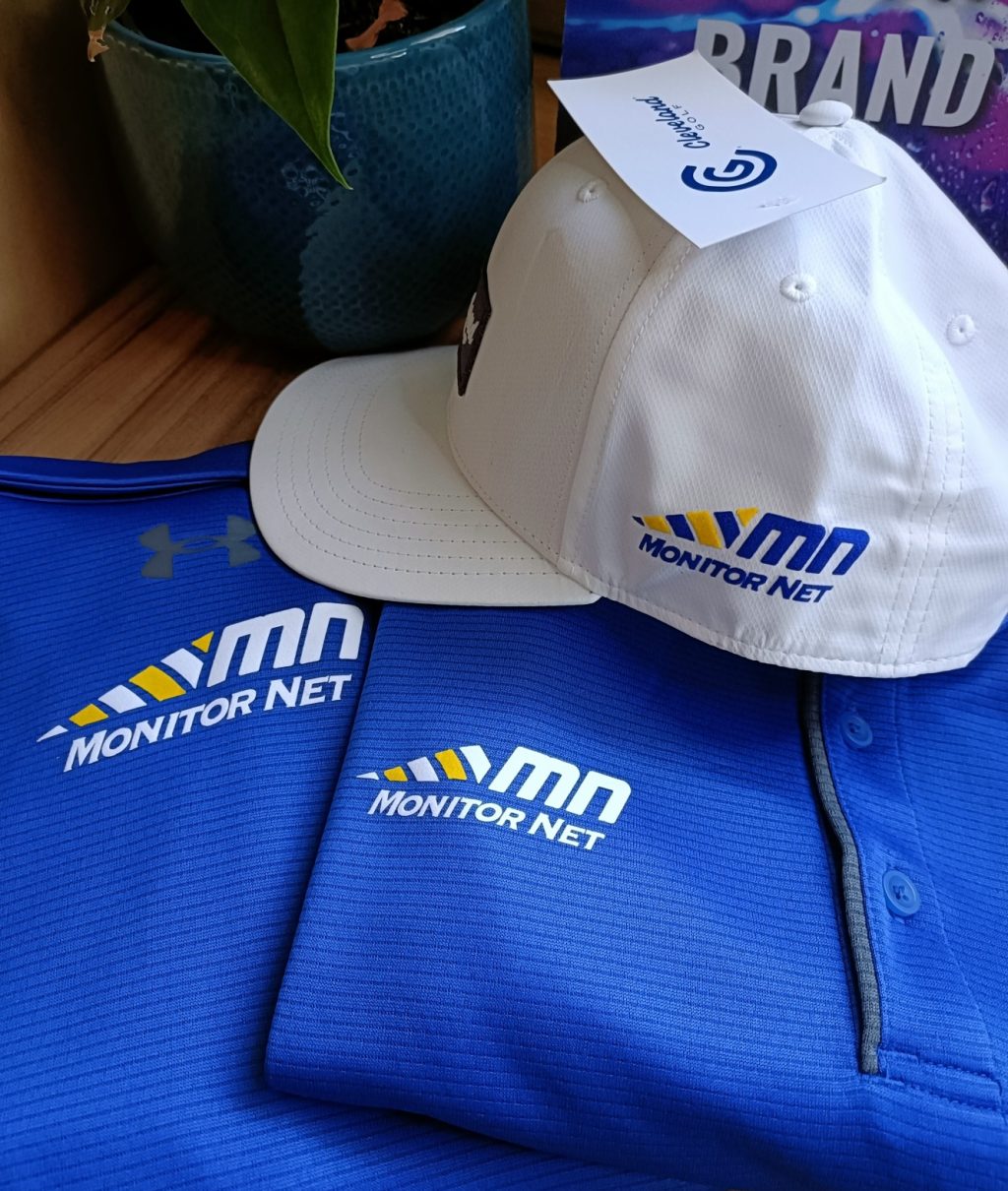Blue Monitor Net branded polo shirts with a matching white logo-branded cap, supplied by Merakology Creative Studio.
